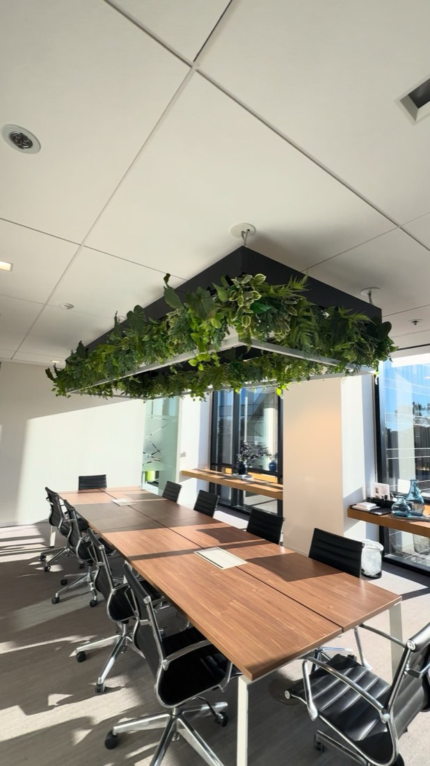 Greenery fixture suspended from the ceiling above a boardroom conference table
