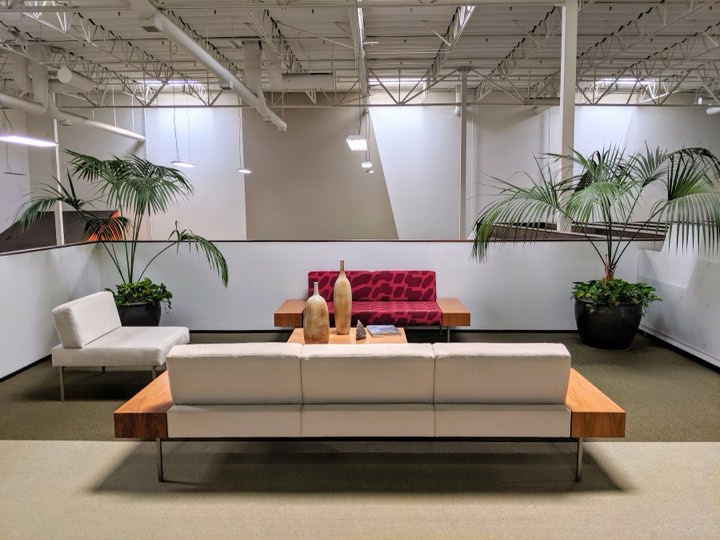 Symmetrical mezzanine lounge with two large kentia palms flanking white and magenta sofas