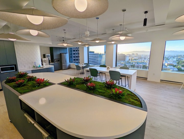 High-rise kitchen island with inset moss-and-bromeliad planter beds and a sunset city view