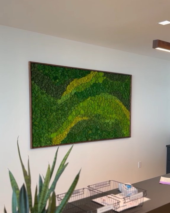 Framed moss-art panel with a chartreuse wave pattern above an office reception desk